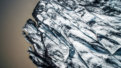 Aerial, Top view. Skaftafell National Park. Ice and ashes of the volcano texture landscape, beautiful nature ice background from Iceland. Sólheimajökull glacier.