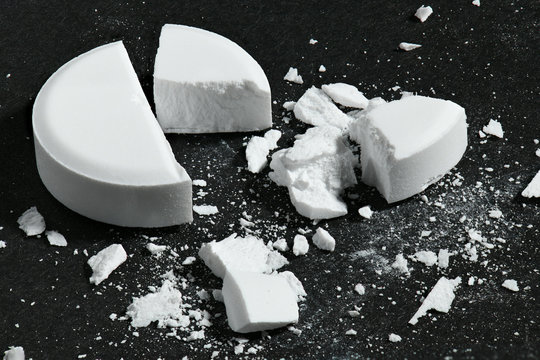 One broken white pill on black background macro photo - concept of medicine and medication treatment, health care