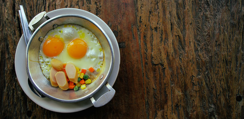 Panoramic banner for website, thai food Fried egg on the pan With chicken sausage, corn, carrots, nuts on wooden table