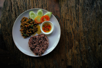 top view of thai food, stir-fried pork spicy and basil served with rice and Cucumber, tomato in white round dish, thai food on wooden table with copy space