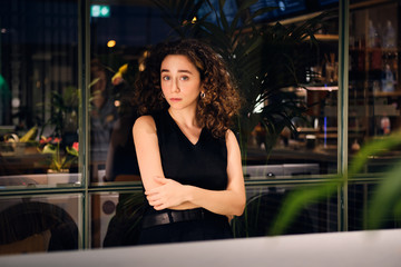 Beautiful girl intently looking in camera by the window in self-service laundry at night
