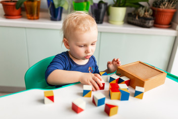 Baby playing with wooden blocks creating a pattern