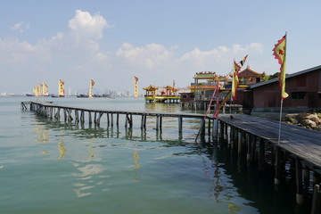 Steg mit Flaggen + chinesischer Tempel auf Stelzen in Georg Town Penang