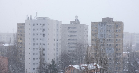 Snow storm with high winds blowing snowflakes sideways, against tall apartment buildings in the back, in Bucharest, Romania.