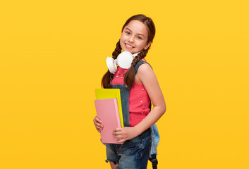 Happy schoolgirl with books and headphones