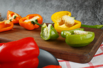 Color bell peppers cut into pieces on a wooden board.