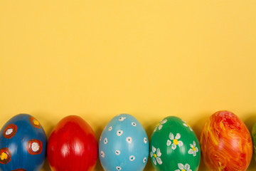 Easter holiday background. Coloured decorated easter eggs on a bright yellow background