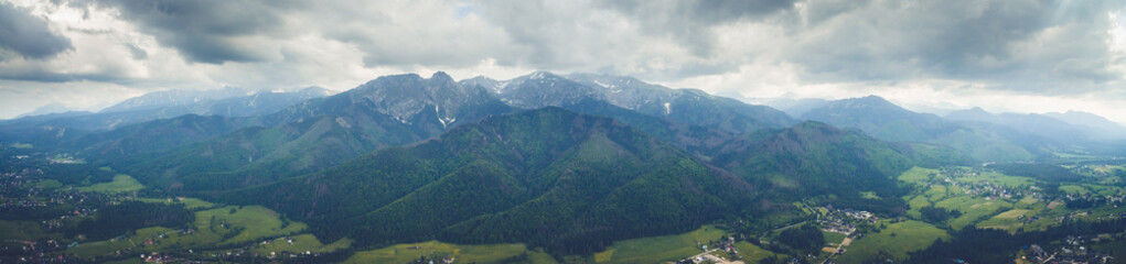 Panoramic drone view of idyllic green town with giant High Tatras mountain range. Zakopane, Poland