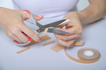 The faceless woman glues kinezio tape. Female hands close-up cut beauty applications for the face....