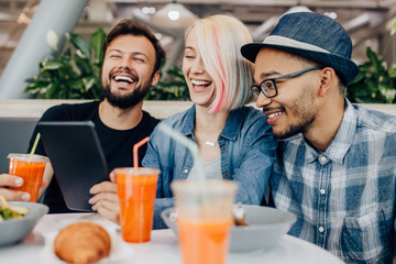 Multiracial friends browsing tablet and laughing after work