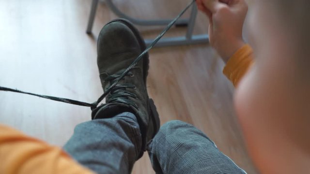 Boy tying shoelaces at school. Child developing motor skills