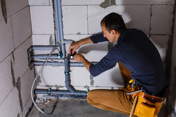 Fototapeta na wymiar plumber makes wiring of sewer pipes
