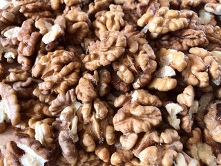 Food background. Top view on a pile of peeled walnuts. Texture of walnut kernels. Background of brown nuts. Close-up, horizontal, cropped shot. Concept of vegetarianism and healthy eating.