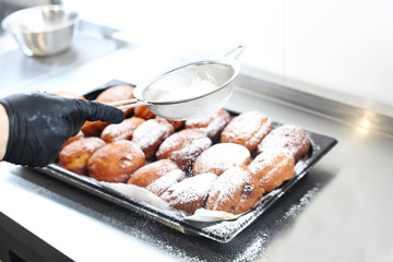 Confectionery, traditional yeast donut with powdered sugar. Donut, a traditional donut with filling and powdered sugar. Confectioner sprinkles sugar on fried cookies.