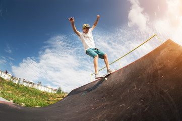 Portrait of a young skateboarder doing a trick on his skateboard on a halfpipe ramp in a skate park...