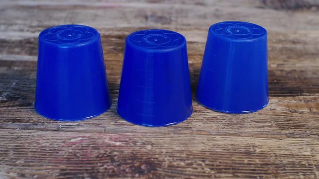 thimblerig.a hidden pea under one of the glasses moves them around the table