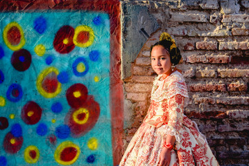 Beautiful girl fallera wearing the traditional Valencian costume of Fallas, during a beauty session and posing outdoors.
