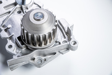 Close-up New metal automobile pump for cooling the engine of a water pump on a gray background. The concept of new spare parts for the car engine