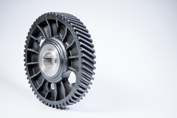 Black polymer gear camshaft with metal base. New spare part for an internal combustion engine on a gray background