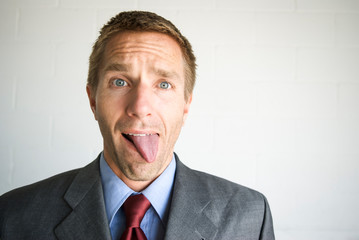 Tired businessman sticking his tongue out with a confused expression