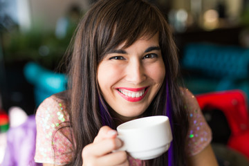 Portrait of young stylish trendy woman with multi-coloured strand in hair sits in cafe