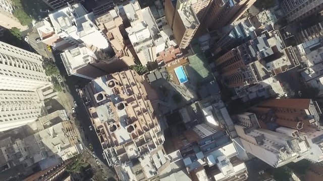 Vuelo sobre ciudad, vista cenital de los edificios y las calles, piscinas en terrazas, autos, calles
