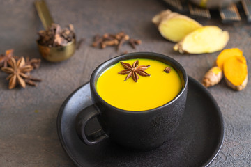 Obraz na płótnie Canvas Close up of Ayurvedic drink Golden milk made with ginger, turmeric, spices and milk in mag on concrete background. Alternative remedies for health