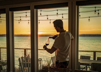 Red wine pouring into glass under deck lights at sunset.