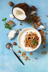 Homemade healthy breakfast. Bowl with homemade baked coconut granola and greek yogurt on a turquoise stone or concrete table.  Top view flat lay background.