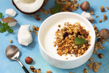 Homemade healthy breakfast. Bowl with homemade baked coconut granola and greek yogurt on a turquoise stone or concrete table.
