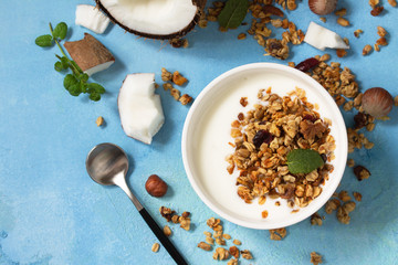 Homemade healthy breakfast. Bowl with homemade baked coconut granola and greek yogurt on a turquoise stone or concrete table.  Top view flat lay background.