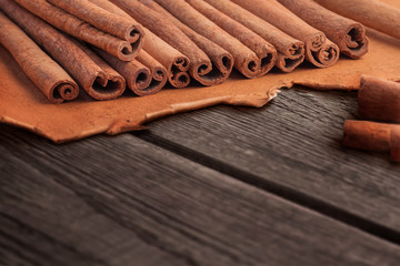 Closeup of a bunch of cinnamon sticks on brown paper on a wooden textured background with copy space.