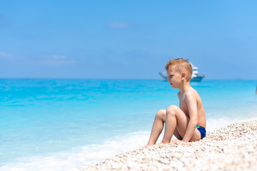 A boy is sitting and looking on the water