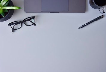 A worktable with laptop, glasses, homemade flower, pen and mug of proper coffee and a place for your own text