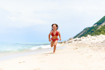 Fototapeta na wymiar Cute little girl is running by the water