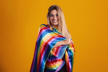 Young blonde hair woman in costume enjoying the carnival party covering with lgbt pride t-shirt. Alone. One. LGBT flag. LGBT+ symbol on yellow background.