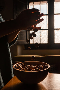 Unrecognizable person grabbing full of tasty fresh hazelnut on brown wooden bowl