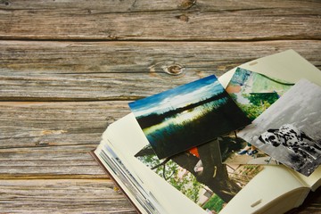 Naklejka na ściany i meble Photo album and strewn colorful various photographs on a wooden table
