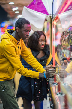 Black man playing claw crane for girlfriend