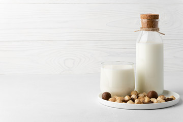 Dairy-free milk. Macadamia nut milk in a glass cup and a bottle on a white background. Dairy products without lactose. Copy space.