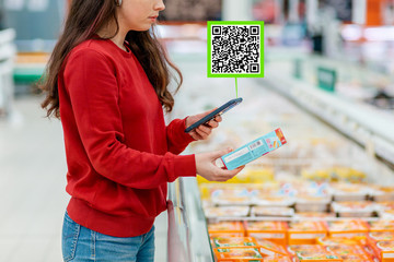 A young Caucasian woman scans the qr code on the packaging of a semi-finished product using...