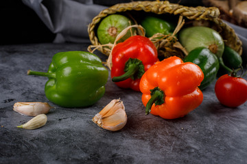 Removing bell peppers and garlics from a rustic basket.