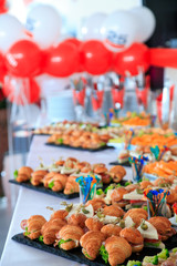 Mini croissants appetizers with salad and meat in plate on banquet table. Catering snacks for birthday party.
