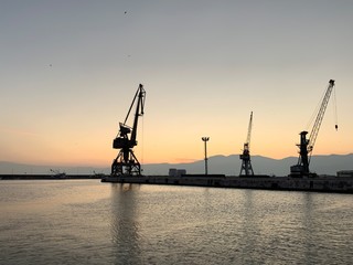 Silhouettes of the sea port cranes background at the sunset, natural colors