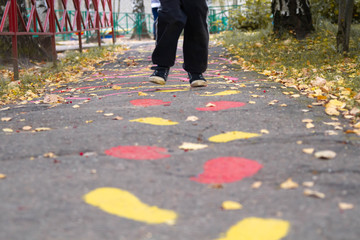 The boy runs on the asphalt. Traces of human paint on the road.