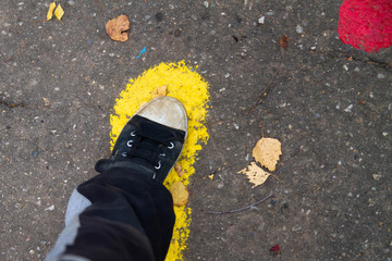 The boy follows the tracks on the pavement. Traces of paint on the road.