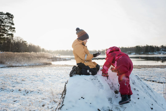 siblings playing together by the Baltic Sea in the snow at winter