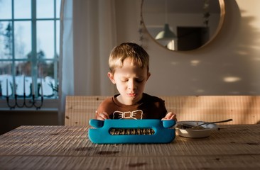 young boy playing in his iPad at home whilst eating breakfast