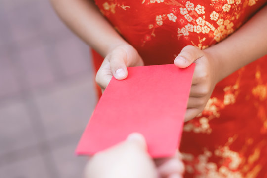 People giving red envelope (ang pao) to child.