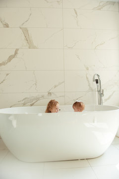 little brother and sister bathing in a foam bath